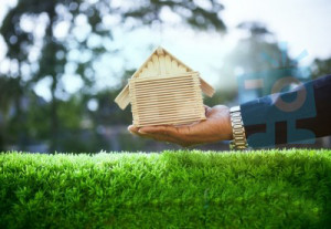 hand-of-business-man-and-wood-house-model-on-beautiful-green-gra-100255663 copy